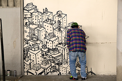 Photo of a local urban artist painting a mural under the I-70 viaduct during the 'duct-work Event (September 30, 2016).